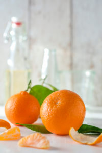 Clementinen mit Laub, Clementinenstücke und Schale vor hellem Hintergrund, Clementinen mit Laub, Clementinenstücke und Schale vor hellem Hintergrund,